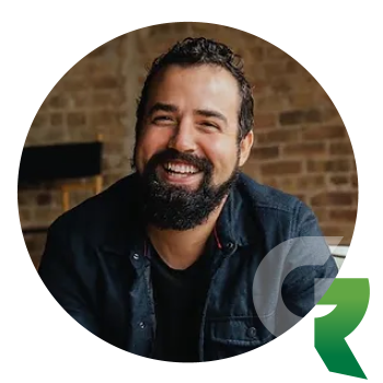 A smiling man with a full beard wearing a dark jacket.