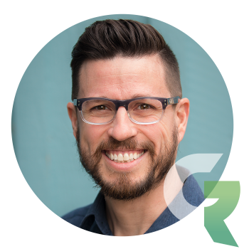 Headshot of a smiling man with a beard and glasses.