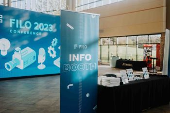 A blue banner for the FILO 2023 conference info booth standing in a lobby.